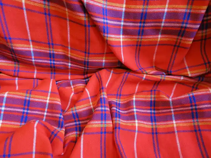 A red check cloth with blue and white stripes lying in deep soft folds